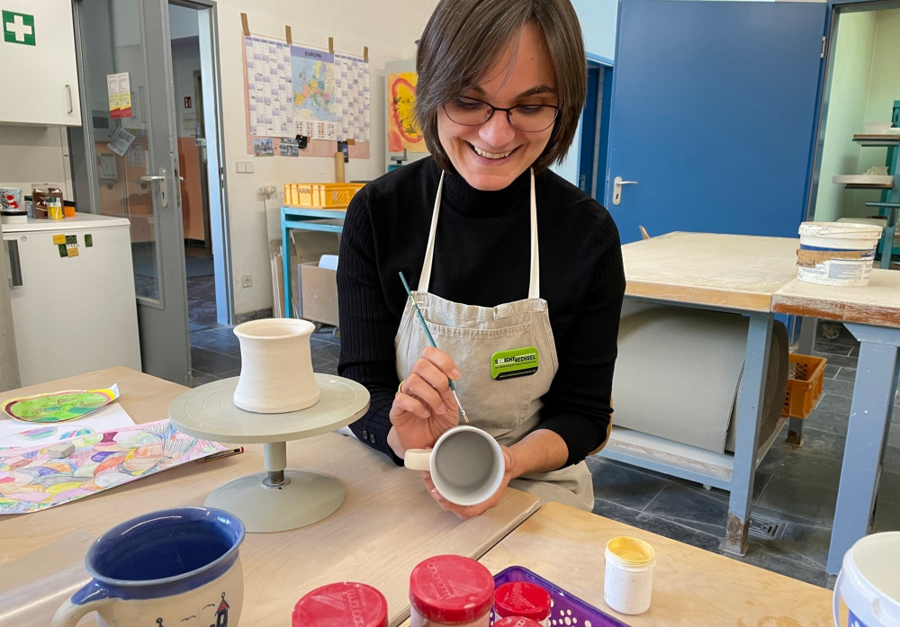 Schichtwechslerin Carola König bemalt eine Tasse